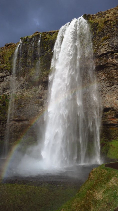 The midnight sun casts a rainbow at Skógafoss.